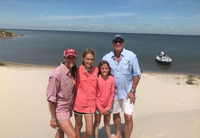 The Glenn family smiles together on a lake